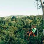 man on zipline in front of jungle