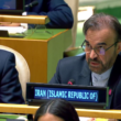 A man in a suit and glasses speaks at a United Nations meeting, seated behind a sign reading "Iran (Islamic Republic of)".