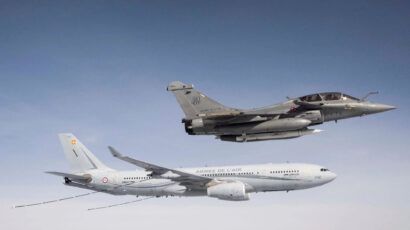 A French military jet flies above a French Air Force refueling aircraft in midair against a clear sky.