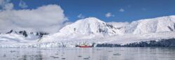 red research ship next to edge of Antarctic ice